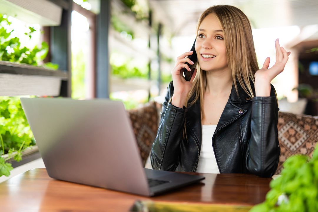 person on phone with laptop on table